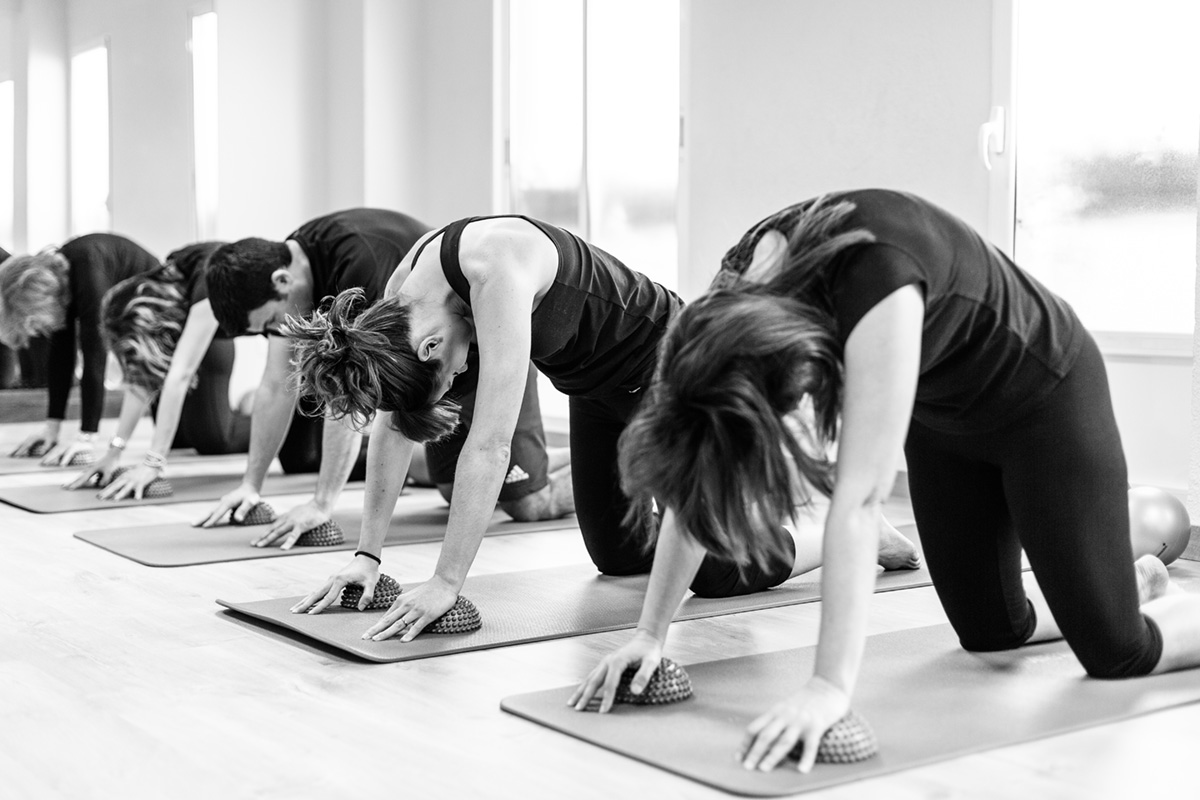 Clase grupal de reeducación postural: alineación de columna en cuadrupedia.